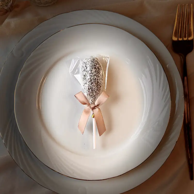 Sucette de dattes à la noix de coco, nœud satiné, posée au centre de l’assiette d’un invité