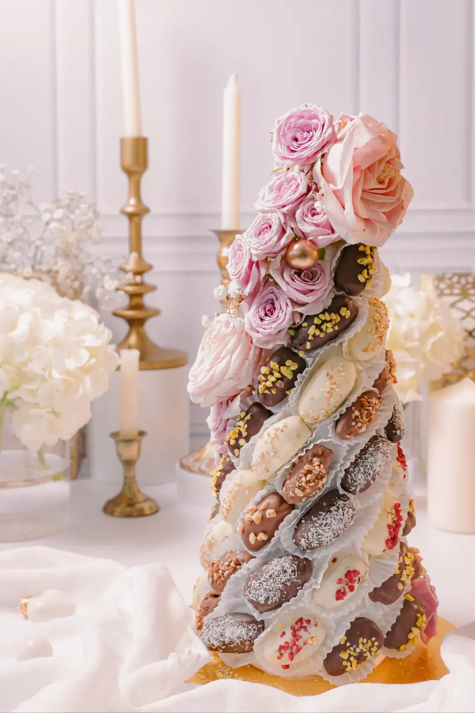 Cône de dattes enrobées de chocolat, couronné de roses, sur une table de réception
