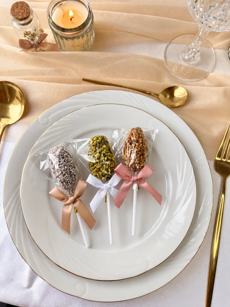 Trois sucettes de dattes posées sur une assiette de mariage, nœuds satinés
